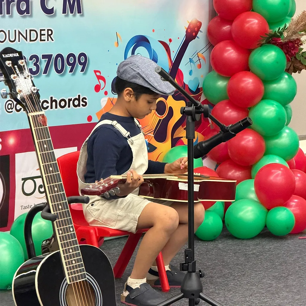 A young student playing guitar on stage at a CforChords showcase